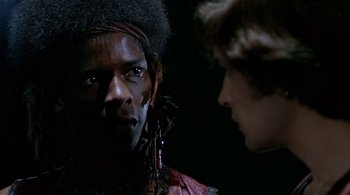 Movie still from “The Warriors” (1979), directed by Walter Hill – A man in a red shirt is looking at another man; Close Up shot, Over the shoulder angle