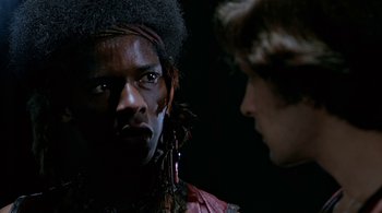 Movie still from “The Warriors” (1979), directed by Walter Hill – A man with a black face is looking at another man with a black face; Close Up shot, Over the shoulder angle