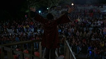 Movie still from “The Warriors” (1979), directed by Walter Hill – A man standing on a railing in front of a crowd of onlookers; Extreme Wide shot, High angle