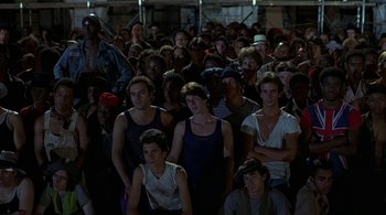 Movie still from “The Warriors” (1979), directed by Walter Hill – A large group of young men standing in front of a building; Wide shot, High angle