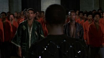 Movie still from “The Warriors” (1979), directed by Walter Hill – A group of men standing next to each other in a room; Medium shot, Over the shoulder angle