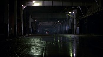 Movie still from “The Warriors” (1979), directed by Walter Hill – A car driving down a street under a bridge; Extreme Wide shot, High angle