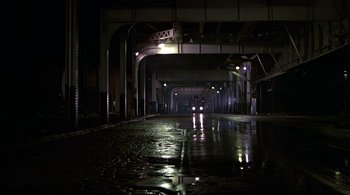 Movie still from “The Warriors” (1979), directed by Walter Hill – A car driving down a wet street at night; Extreme Wide shot, Low angle