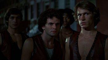 Movie still from “The Warriors” (1979), directed by Walter Hill – A group of men standing next to each other in a dark room; Close Up shot, Low angle