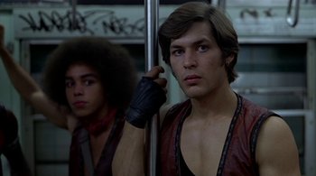 Movie still from “The Warriors” (1979), directed by Walter Hill – Two young men are standing next to each other on a bus; Close Up shot, Over the shoulder angle
