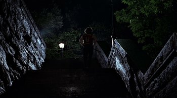 Movie still from “The Warriors” (1979), directed by Walter Hill – A person is walking down a bridge at night; Wide shot, Low angle