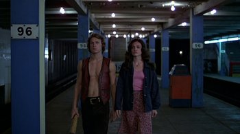 Movie still from “The Warriors” (1979), directed by Walter Hill – A man and a woman are walking in a train station; Medium shot, Low angle