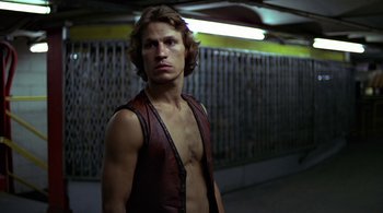 Movie still from “The Warriors” (1979), directed by Walter Hill – A man in a leather vest standing in a subway station; Medium shot, Low angle