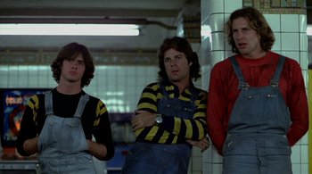 Movie still from “The Warriors” (1979), directed by Walter Hill – A group of men standing next to each other in a building; Medium shot, Low angle