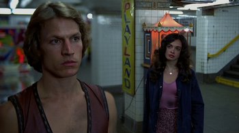 Movie still from “The Warriors” (1979), directed by Walter Hill – A man and a woman standing next to each other; Medium shot, Over the shoulder angle