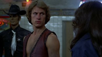 Movie still from “The Warriors” (1979), directed by Walter Hill – A man with long hair wearing a leather vest; Close Up shot, Over the shoulder angle