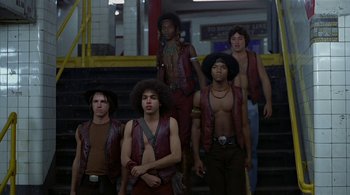 Movie still from “The Warriors” (1979), directed by Walter Hill – A group of young men standing next to each other on some steps; Wide shot, Low angle