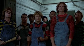 Movie still from “The Warriors” (1979), directed by Walter Hill – A group of men standing next to each other in front of a tiled wall; Medium shot, Low angle