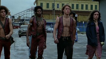 Movie still from “The Warriors” (1979), directed by Walter Hill – Two men are walking down the street shirtless; Medium shot, Low angle