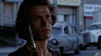 Movie still from “The Warriors” (1979), directed by Walter Hill – A man holding a cell phone up to his ear; Close Up shot, Low angle