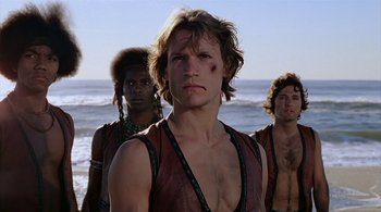 Movie still from “The Warriors” (1979), directed by Walter Hill – A group of men standing on top of a beach; Close Up shot, Low angle