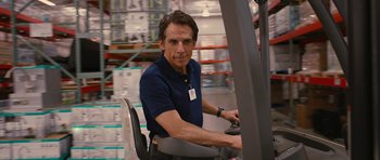 Movie still from “The Watch” (2012), directed by Akiva Schaffer – A man sitting in a forklift in a room filled with boxes; Medium shot, Over the shoulder angle