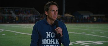 Movie still from “The Watch” (2012), directed by Akiva Schaffer – Ben stiller in a no more whoppers t - shirt holding a microphone; Medium shot, High angle