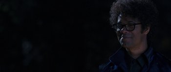 Movie still from “The Watch” (2012), directed by Akiva Schaffer – A person with glasses is smiling for the camera; Close Up shot, Over the shoulder angle