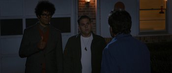 Movie still from “The Watch” (2012), directed by Akiva Schaffer – A man standing next to two other men in front of a building; Medium shot, Over the shoulder angle