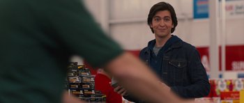 Movie still from “The Watch” (2012), directed by Akiva Schaffer – A young man is smiling at the camera while another looks on; Medium shot, Over the shoulder angle