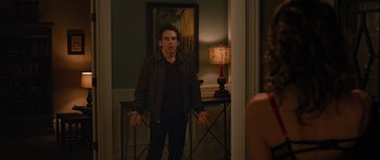 Movie still from “The Watch” (2012), directed by Akiva Schaffer – A man standing in front of a lamp in a room; Medium shot, Over the shoulder angle