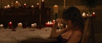 Movie still from “The Watch” (2012), directed by Akiva Schaffer – A woman sitting in front of candles in a room; Medium shot, High angle