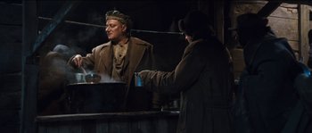 Movie still from “The Way Back” (2010), directed by Peter Weir – Two men are standing in front of a large pot; Medium shot, Low angle