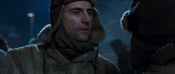 Movie still from “The Way Back” (2010), directed by Peter Weir – A person wearing a jacket and hat; Close Up shot, Low angle