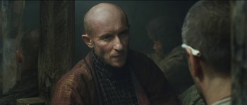 A man with a bald head is looking into the mirror
