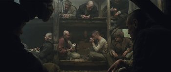 Movie still from “The Way Back” (2010), directed by Peter Weir – A group of men sitting on top of a wooden structure; Wide shot, High angle