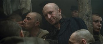 Movie still from “The Way Back” (2010), directed by Peter Weir – A man with a shaved head is looking at the camera; Close Up shot, Over the shoulder angle