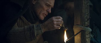 Movie still from “The Way Back” (2010), directed by Peter Weir – An old man lighting a candle in a dark room; Close Up shot, Low angle