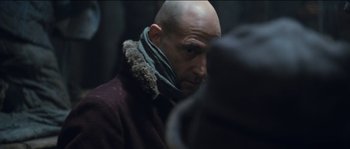 Movie still from “The Way Back” (2010), directed by Peter Weir – A bald man wearing a scarf and a jacket; Close Up shot, Over the shoulder angle