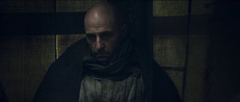 Movie still from “The Way Back” (2010), directed by Peter Weir – A man with a bald head wearing a scarf; Close Up shot, Low angle