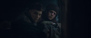 Movie still from “The Way Back” (2010), directed by Peter Weir – A couple of men sitting next to each other in a dark room; Medium shot, Low angle