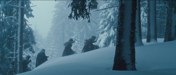 Movie still from “The Way Back” (2010), directed by Peter Weir – A couple of people riding skis down a snow covered slope; Wide shot, Low angle