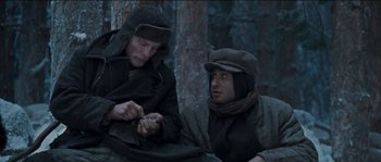 Movie still from “The Way Back” (2010), directed by Peter Weir – Two men sitting next to each other in the woods; Medium shot, Low angle