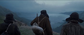 Movie still from “The Way Back” (2010), directed by Peter Weir – A man with a backpack on a hill overlooking the ocean; Wide shot, Low angle
