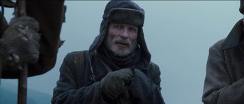 Movie still from “The Way Back” (2010), directed by Peter Weir – An old man wearing a winter coat and hat; Close Up shot, Over the shoulder angle