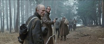 Movie still from “The Way Back” (2010), directed by Peter Weir – A group of men standing in the woods near a forest; Medium shot, Over the shoulder angle