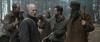 Movie still from “The Way Back” (2010), directed by Peter Weir – A group of men standing next to each other in the woods; Medium shot, Over the shoulder angle