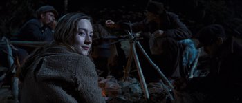 Movie still from “The Way Back” (2010), directed by Peter Weir – A woman sitting in the middle of a forest; Medium shot, Over the shoulder angle