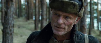 Movie still from “The Way Back” (2010), directed by Peter Weir – An older man wearing a hat in a wooded area; Close Up shot, Low angle