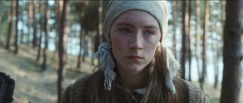 Movie still from “The Way Back” (2010), directed by Peter Weir – A young woman wearing a hat and a scarf in a wooded area; Close Up shot, Low angle