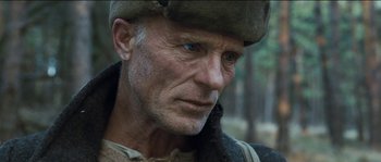 Movie still from “The Way Back” (2010), directed by Peter Weir – An older man wearing a hat and looking at the camera; Close Up shot, Low angle