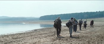 Movie still from “The Way Back” (2010), directed by Peter Weir – Two people walking on the beach with backpacks; Extreme Wide shot, Low angle