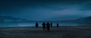 Movie still from “The Way Back” (2010), directed by Peter Weir – A group of people walking on a beach at night; Extreme Wide shot, High angle