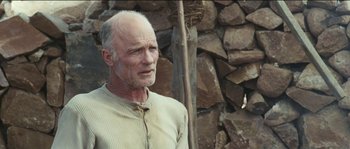 Movie still from “The Way Back” (2010), directed by Peter Weir – An older man standing in front of a stone wall; Close Up shot, Low angle