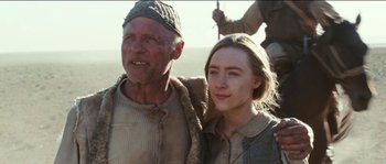 Movie still from “The Way Back” (2010), directed by Peter Weir – A man standing next to a woman in a field; Medium shot, Low angle